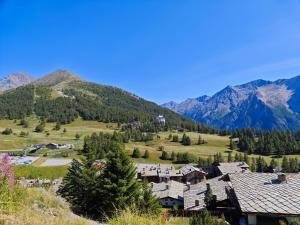 un village dans une vallée avec des montagnes en arrière-plan dans l'établissement Hostdomus - Pastore Apartment, à Sestrières