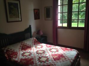 a bedroom with a bed with a red and white quilt at Entre mer et montagne in Hasparren