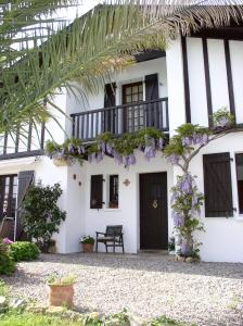 a white house with a balcony with purple flowers at Entre mer et montagne in Hasparren