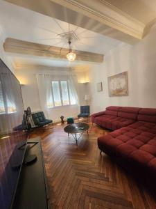 a living room with a red couch and a table at Maison de Maître L Oustal des Halles avec salle de cinéma, billard & Jacuzzi in Castelnaudary +25 photos