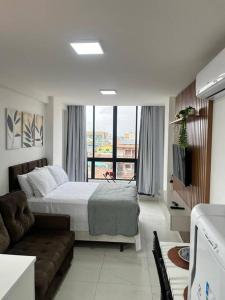 ein Schlafzimmer mit einem Bett und einer Couch und einem Fenster in der Unterkunft Oàsis à beira mar-Porto City 201 in Porto De Galinhas