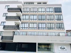 ein hohes weißes Gebäude mit vielen Fenstern in der Unterkunft Oàsis à beira mar-Porto City 201 in Porto De Galinhas