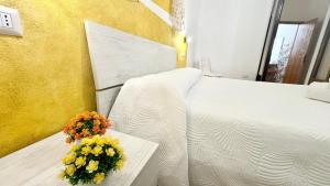 a white bed with a bouquet of flowers on a table at CASA DEL CORSO in Dorgali