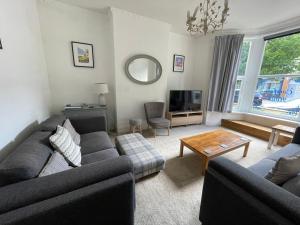 a living room with a couch and a table at Free Parking, Entire 8 Ensuite Bedroom Townhouse, Fully Equipped Kitchen, Dining Room & Lounge, Perfect for Family Gatherings, Long Term Contractor, Relocation, etc Stays, 15 mins to Nissan, 20 mins to Sunderland & Newcastle, See our Site for Assurance in South Shields