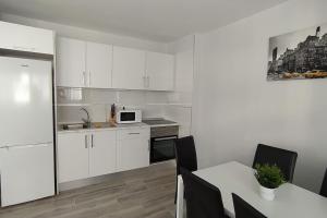 a kitchen with white cabinets and a table with chairs at Apartamento Refugió del Mar in El Médano