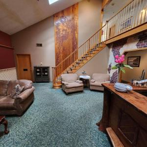 a living room with couches chairs and a staircase at Springbrook Inn AuSable in Houghton Lake