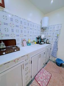 アガディールにあるQuiet Central Home Near Beach - High Speed WiFi, Free Parking & Private Entryの白いキャビネットと花が壁に飾られたキッチン