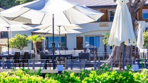 un patio con sombrillas blancas, mesas y sillas en Beach Front Litore, en Shimoda
