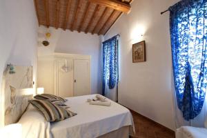 a bedroom with blue curtains and a bed with towels on it at Il Casolare Val Di Mare in Riparbella