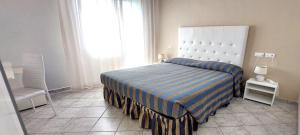 a bedroom with a large bed with a striped bedspread at Hotel Viña del Mar Pineta in Lido di Jesolo