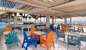 a restaurant with colorful chairs and tables and a pool at Margaritaville Island Reserve Riviera Maya - An Adults Only Karisma All-Inclusive Experience in Puerto Morelos
