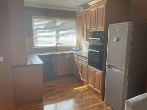 une cuisine avec des armoires en bois et un réfrigérateur blanc dans l'établissement Cute Cottage Central Bathgate, à Bathgate