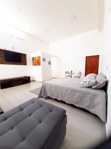 two beds in a white room with a couch at Casa Loft da Orla in Barra Bonita