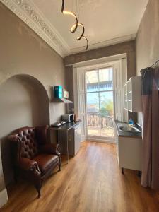 a living room with a chair and a kitchen with a window at Balcony Flat next to Port, Sea view, Free Parking in Dover