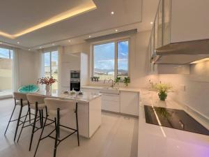 a large white kitchen with a island with bar stools at Jabal Akhdar Rummana Villa in Al ‘Aqar