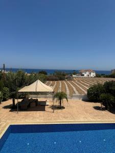 a blue swimming pool with a tent and a view of a vineyard at Villa Dafni Malama in Paralimni