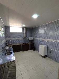 eine große Küche mit blauen Fliesenwänden und einer Spüle in der Unterkunft Casa de Temporada Preciosa in Novo Airão