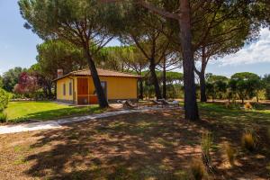une petite maison jaune dans un parc avec des arbres dans l'établissement Tenuta Fiumara, à Marina di Grosseto 73 autres photos