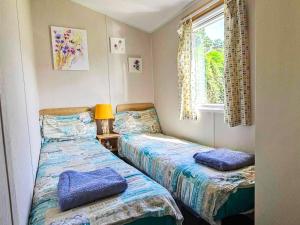 two beds in a small room with a window at Dog Friendly 8 Berth Static Caravan Newquay in Newquay +24 photos