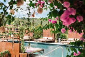 a swimming pool with benches and pink flowers at Finca Legado Ibiza in Santa Eularia des Riu