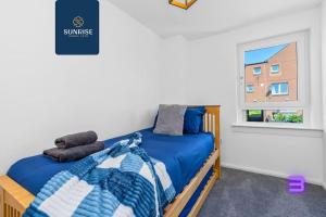 a bedroom with a bed with blue sheets and a window at Springhill Townhouse - INVOICE and REDUCED PRICE only via SUNRISE SHORT LETS DUNDEE, 3 Bedrooms, 2 Kings, 1 Single, Great Views, Newly Refurbished, Free Parking, Free Wifi, River View, Dock, Eden Views in Dundee