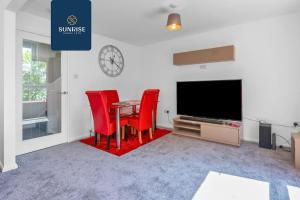 a dining room with red chairs and a table and a tv at Springhill Townhouse - INVOICE and REDUCED PRICE only via SUNRISE SHORT LETS DUNDEE, 3 Bedrooms, 2 Kings, 1 Single, Great Views, Newly Refurbished, Free Parking, Free Wifi, River View, Dock, Eden Views in Dundee