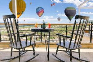 Dos sillas con globos aerostáticos en el cielo. en Karlık Cave Suite Cappadocia, en Uchisar
