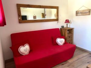a red couch with two pillows on it in a room at Appart à Puy Saint Vincent 1700 Rés Emeraude in Puy-Saint-Vincent