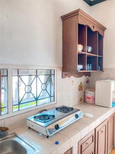 une cuisine avec une cuisinière, un évier et des fenêtres dans l'établissement Villa Kota Bunga Aeshtetic By akuvilla, à Cikundul