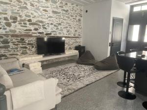 a living room with a couch and a tv at The Bridge House Plomari in Plomari