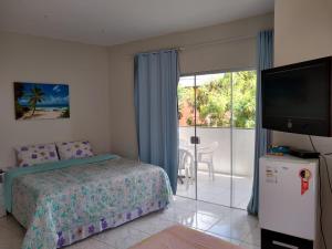 a bedroom with a bed and a flat screen tv at Pousada Caribe in Itacimirim