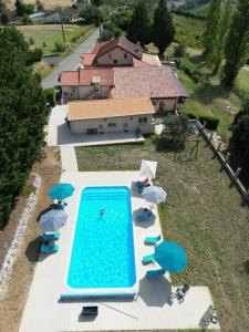 an aerial view of a swimming pool with umbrellas and a house at Logis des Crêtes de Pignols in Moissac