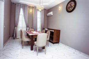 a dining room with a table and chairs and a clock at Whitehall apartment in Yenagoa +4 photos
