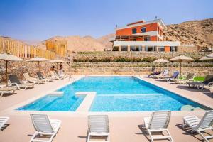 a pool with chairs and a house in the background at Casa Dama in Cieneguilla
