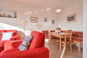 ein Wohnzimmer mit roten Möbeln und einem Tisch in der Unterkunft Bungalow Vaupel in Kellenhusen