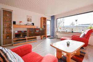 ein Wohnzimmer mit roten Stühlen und einem Tisch in der Unterkunft Bungalow Vaupel in Kellenhusen