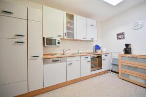 eine Küche mit weißen Schränken und einer Spüle in der Unterkunft Bungalow Vaupel in Kellenhusen + 7 Fotos