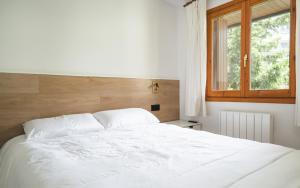 a white bed in a bedroom with a window at La gran plaza de candanchu in Candanchú
