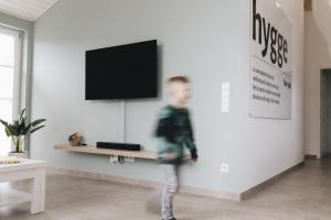 a young boy walking in a living room with a tv at SeeHus - Nordhorn in Nordhorn +28 photos