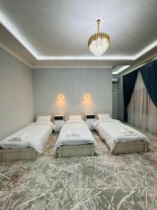 a large bedroom with three beds and a chandelier at Hotel Soro in Samarkand