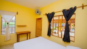 a bedroom with a bed and two windows at La Playa hostel in Mazunte