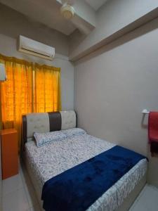 a bedroom with a bed with a blue blanket and a window at Dhiyaa's Homestay, Belleza in Jitra +11 photos