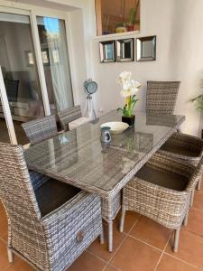 a dining room table with wicker chairs and a glass top at Casa Paradise 2, Ground Floor Apartment on Mar Menor Golf Resort in Torre-Pacheco