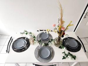 a white table with plates and vases on it at Idéalement situé pour tous II in Dijon