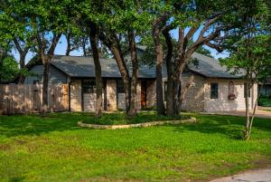 a brick house with trees in a yard at Serene Family Retreat King Beds Pool Hot Tub and Games in Cedar Park