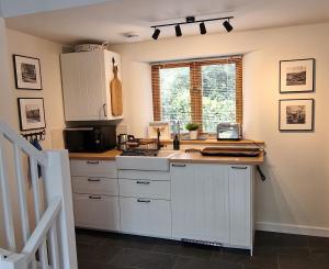 une cuisine avec des armoires blanches et un comptoir dans l'établissement Keep Cottage, à Southleigh