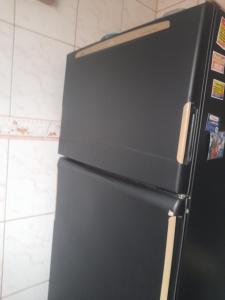 a black refrigerator freezer sitting in a kitchen at Casa Cinza in São Gonçalo