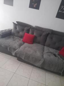 a brown couch with two red pillows on it at Casa Cinza in São Gonçalo