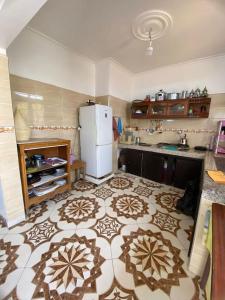 a kitchen with a white refrigerator and a tile floor at Maison Entière Reposante à 5km de Oualidia in El Akarta