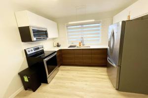 a kitchen with a stainless steel refrigerator and wooden cabinets at Beautiful and Spacious 3 BDR 3 Beds Home in Winnipeg